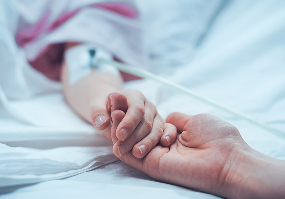 Un paciente dado de la mano de un familiar | © gorodenkoff · iStock